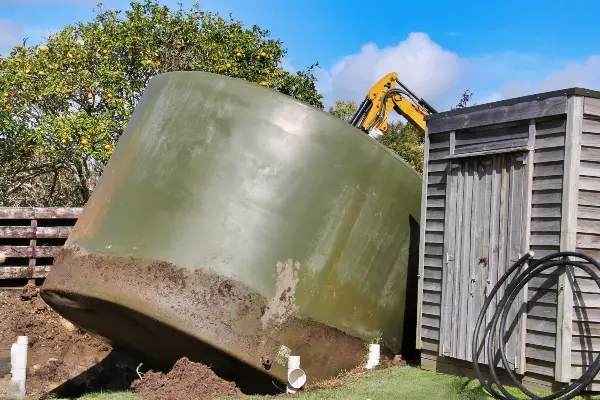 Aqua Works removing an old water tank with a digger during a tank replacement