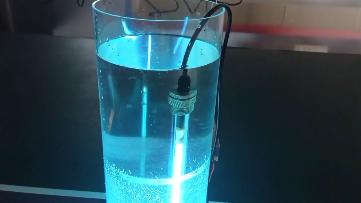 UV lamp glowing inside a quartz sleeve, shown in a glass of water