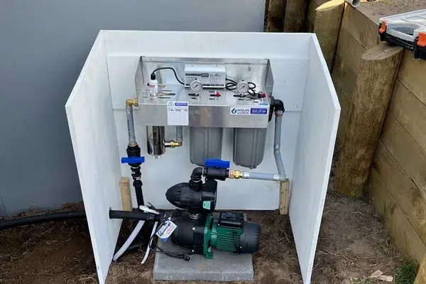 Aqua UV water filter system with twin sediment filters and a water pump inside a white cover box at a new home in Mangawhai Heads