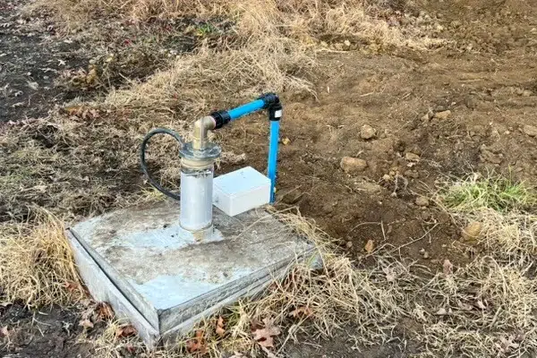 Bore head with the pump outlet and wiring on a concrete pad at a property in Coatesville
