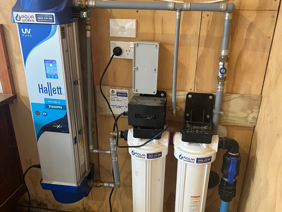 Hallett validated UV system with twin cartridge filters on a plywood wall in a commercial plant room