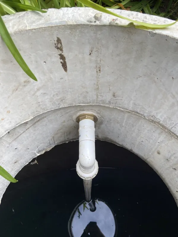 Water running into a concrete water tank at a Matakana home with a pH neutraliser