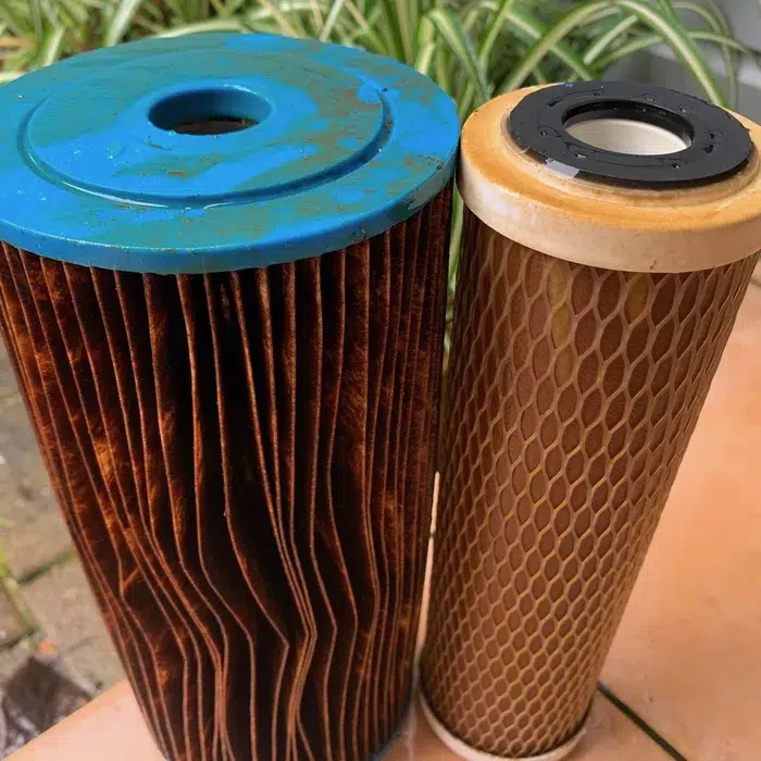 Pleated sediment cartridge and carbon block cartridge, both stained brown with sediment