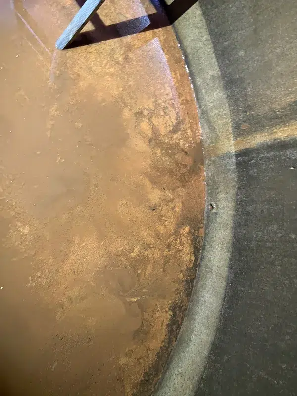 Brown, muddy water and settled sediment inside a concrete water tank