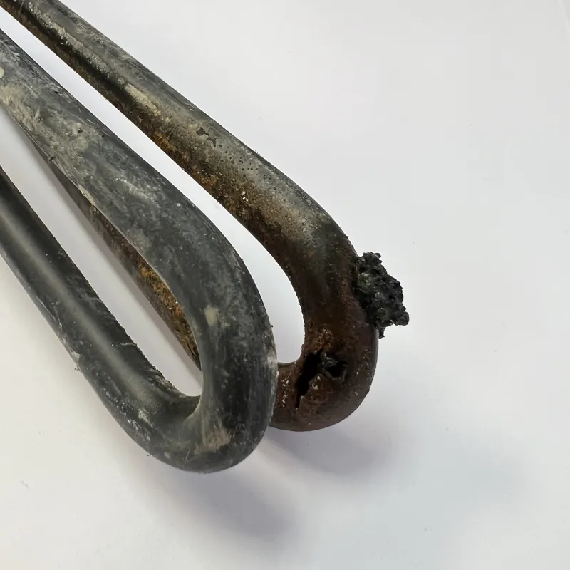 Hot water cylinder element coated in scale that has failed at the tip