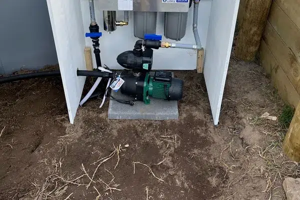 Pressure pump in a pump box beside a rainwater tank