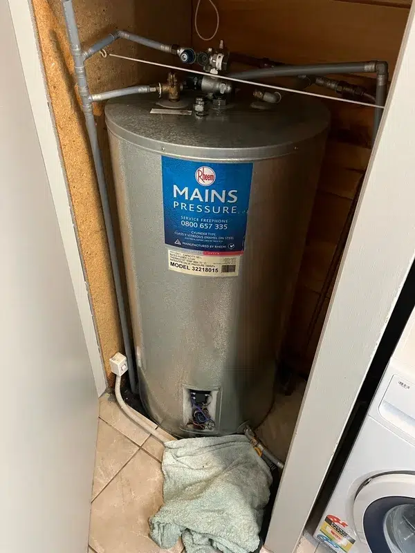 Leaking mains pressure hot water cylinder with a towel on the floor