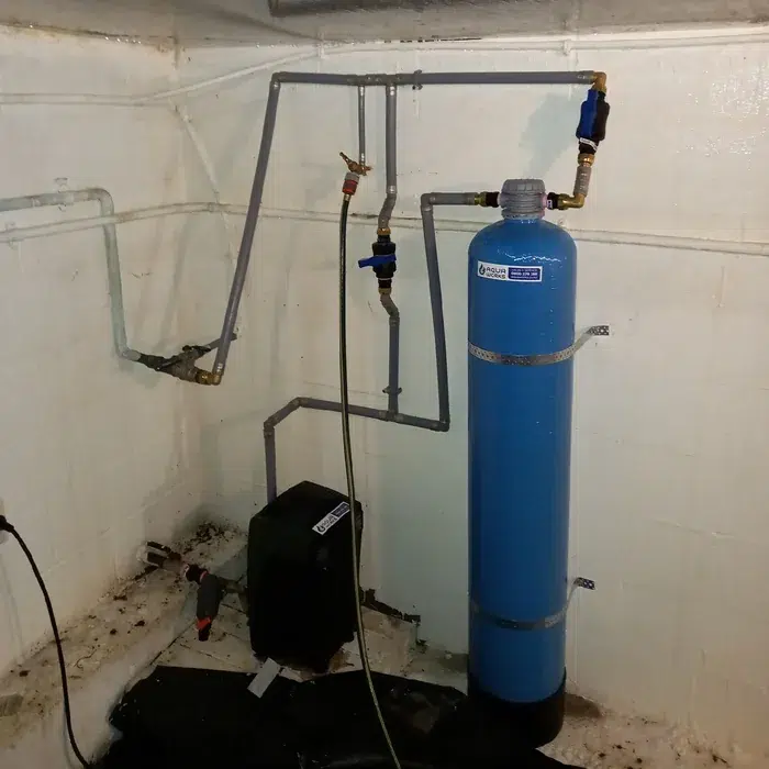 Blue upflow pH neutraliser and water pump in a concrete pump shed at Stillwater