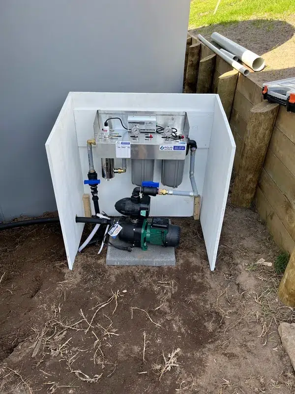 Pressure pump, twin cartridge filters and a UV system in a pump box beside a water tank