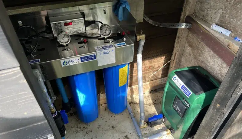 Viqua UV system and twin big blue filters on a stainless bracket in a pump shed, next to a green DAB pump, on the outskirts of Kaukapakapa